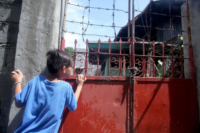 FIRE VICTIMS. A young resident peeks behind the metal gate of Tourism assistant secretary Eden Josephine David’s house which was gutted by fire early morning of Saturday. David’s nine-year old son and a house help died while the assistant secretary and a house boy were injured during the incident. Lean Daval Jr.