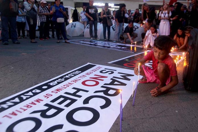 A boy lights a candle as he joined the national day of unity and rage against the Marcos burial at the Libingan ng mga Bayani protest rally at the Freedom Park along Roxas Avenue in Davao City on Friday evening. LEAN DAVAL JR.