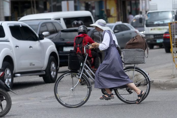 Easy does it. A nun maneuvers her bicycle through the long queue of vehicles after buying goods at the junction of J.P. Laurel Avenue and Angliongto Street in Davao City yesterday. Lean Daval Jr.