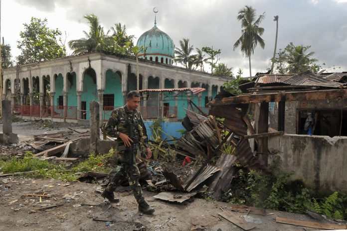 A soldiers walks past a bombed-out mosque in Butig town in Lanao del Sur on Thursday. Government troops retook Butig town a day earlier, after being occupied by the Maute group for days. But it took a day to clear the town of unexploded ordnance. MindaNews photo by Froilan Gallardo