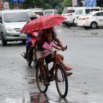 IT COMES WITH PRACTICE. A father holds an umbrella on one hand to cover his daughter from heavy rains and uses the other hand to maneuver his bicycle while traversing E. Quirino Avenue in Davao City over the weekend. LEAN DAVAL JR