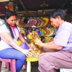 SPRUCING UP. Religious items vendor Sonia Morial (right) changes the dress of a miniature Black Nazarene image owned by a devotee at her stall inside San Pedro Cathedral compound in Davao City two days before the celebration of the Feast of the Black Nazarene.  LEAN DAVAL JR.