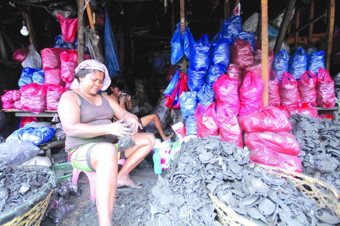 UNSURE OF TOMORROW. Trader Rosemarie Tejero repacks charcoal while discussing with her fellow traders the possible effects of the government’s plan to stop the ‘5-6’ lending scheme of Indian lenders on their business. Majority of small business owners at Agdao Public Market get their capital from loan sharks. LEAN DAVAL JR.
