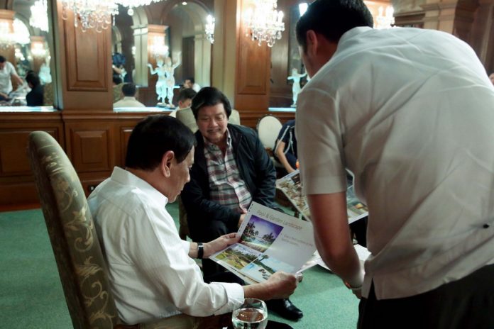 VANTAGE VIEW. President Rodrigo Roa Duterte examines the plan for a real estate development project in Davao City which was handed to him during a meeting with the Gatchalian brothers at the Music Room of Malacañan Palace on Tuesday night. REY BANIQUET/Presidential Photo