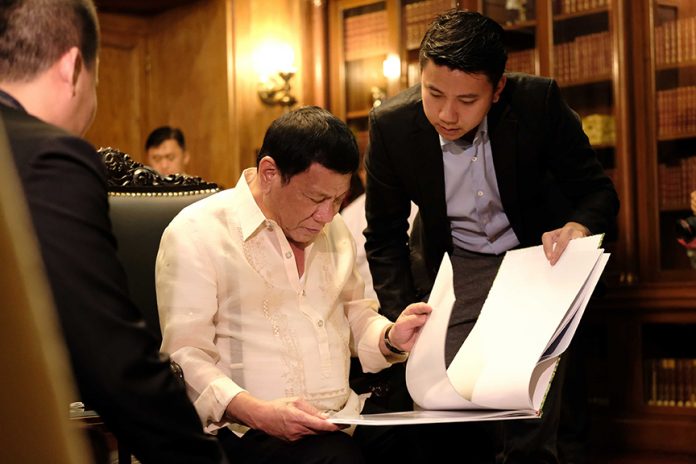 FOR CONSIDERATION. President Rodrigo Roa Duterte scans the document containing the proposal of Chinese businessman, Jose Kho, who has expressed his intent of funding a new rehabilitation center which is proposed to be constructed in Visayas or Mindanao during a meeting at the Music Room in Malacañan Palace on Tuesday evening. ACE MORANDANTE/ Presidential Photo