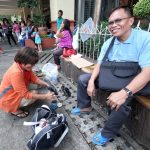 WAITING. A man waits as a shoeshine lady cleans up his shoes outside Sangguniang Panlungsod along San Pedro Street in Davao City yesterday. LEAN DAVAL JR.