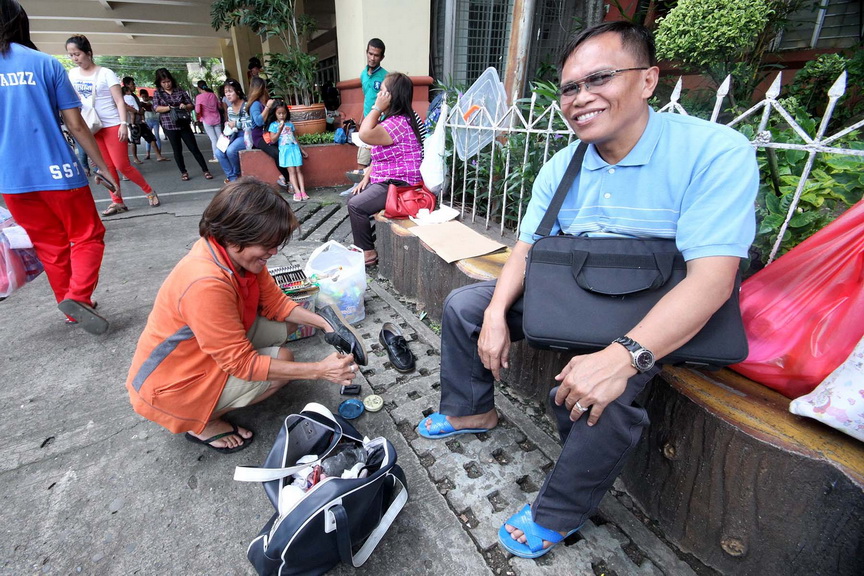 WAITING. A man waits as a shoeshine lady cleans up his shoes outside ...