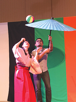 Daikagura Lucky Mai shows a volunteer how to juggle a ball on an umbrella