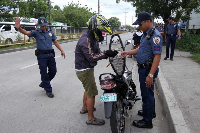 ROUTINE CHECK. A police personnel from Sta. Ana Police Station inspects a rider’s license at a checkpoint along R. Castillo Street in Davao City on Good Friday as part of a tighter security measures being implemented by authorities in the city during the Holy Week. LEAN DAVAL JR.