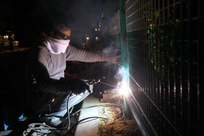 CATCH-UP WORK. A worker from a construction company commissioned by the city government of Davao works on the metal barriers being installed at the center island along R. Castillo Street in Davao City on Monday evening. LEAN DAVAL JR.