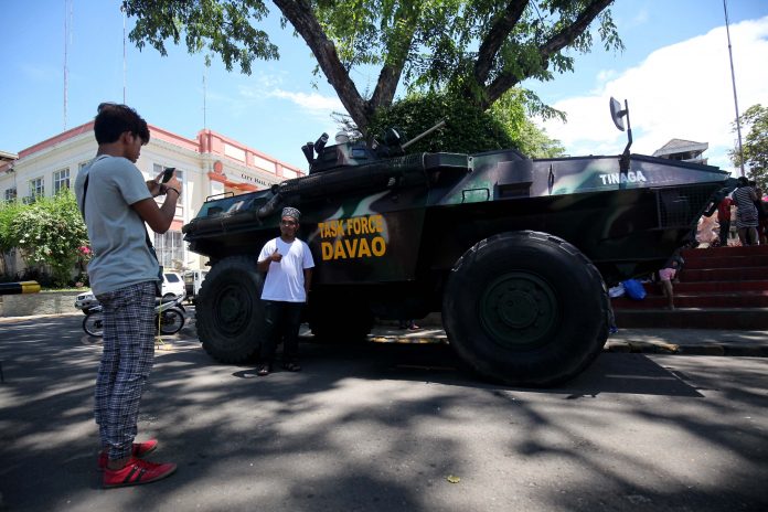 PHOTO OPPORTUNITY. A Muslim resident has his photograph taken with Task Force Davao’s light armor vehicle parked in front of the City Hall of Davao on Saturday. The Muslim community in Davao City, which celebrated the start of Ramadan Saturday morning, has no opposition on the martial law declared by President Duterte. LEAN DAVAL JR.