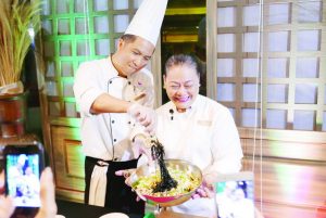 RBE Manager Chel Galang cooks up a bowl of Pancit Pusit able assisted by Executive Chef Alex Destriza