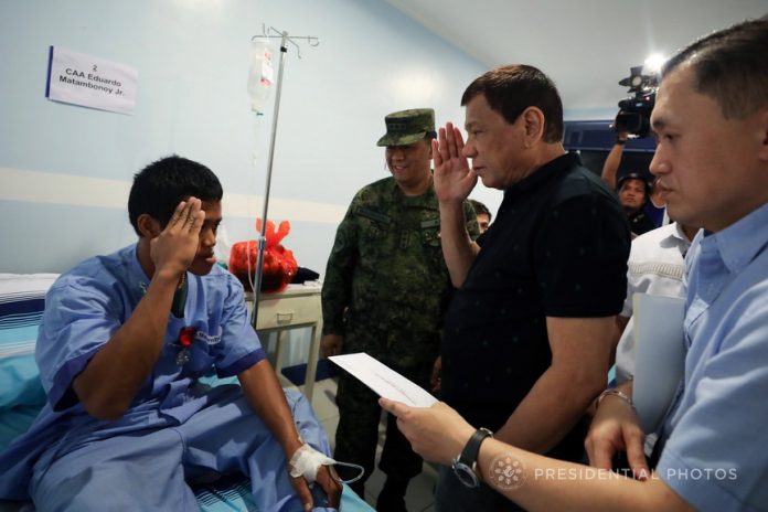 DESERVING. President Rodrigo Duterte salutes CAA Eduardo Matambonoy Jr. after he was awarded with the Order of Lapu-LapuKampilan Medal during the President's visit at Camp Panacan Station Hospital in Davao City on Saturday evening. Matambonoy was wounded in an encounter with members of the New People's Army (NPA) in Tagum City on November 17, 2017. Also in the photo is Special Assistant to the President Christopher Lawrence Go. PRESIDENTIAL PHOTO