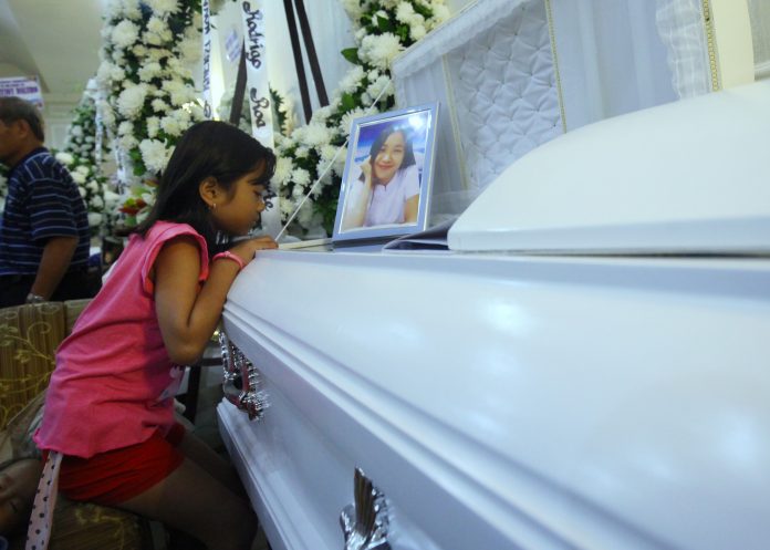 FIRE VICTIM. August watches her aunt Rhenzi Nova Muyco as she sits beside her coffin at Cosmopolitan Funeral Homes along Camus Street in Davao City on Wednesday night. Muyco is among the fatalities during Saturday’s NCCC fire. LEAN DAVAL JR.