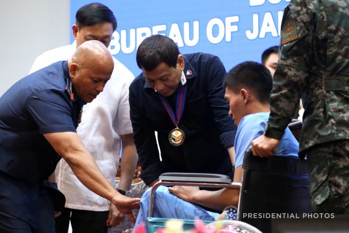 PAT IN THE BACK. President Rodrigo Duterte and Philippine National Police Director General Ronald dela Rosa examine the injury of one of the Order of Lapu-Lapu Kampilan Medal awardees during the awarding ceremony at Camp Brigadier General Rafael Crame in Quezon City on Monday evening. PRESIDENTIAL PHOTO