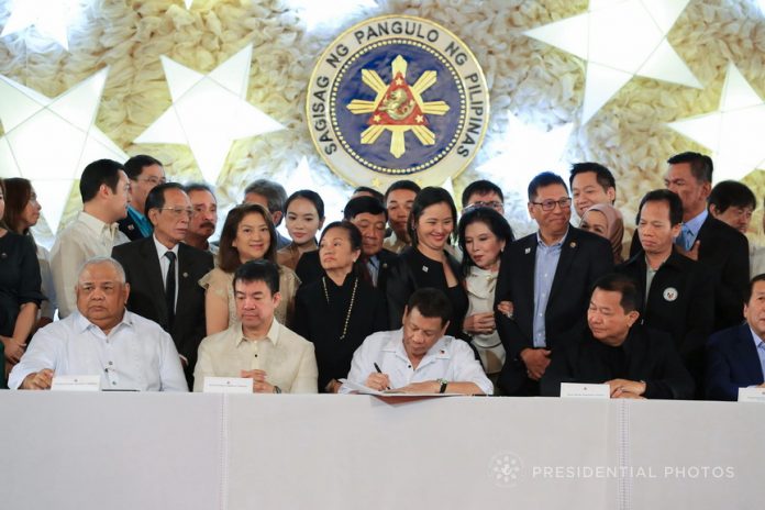 LANDMARK LEGISLATION. President Rodrigo Duterte is flanked by lawmakers as he leads the ceremonial signing of the 2018 General Appropriations Act (GAA) and Tax Reform Acceleration and Inclusion (TRAIN) at the Malacañan Palace on Tuesday. PRESIDENTIAL PHOTO