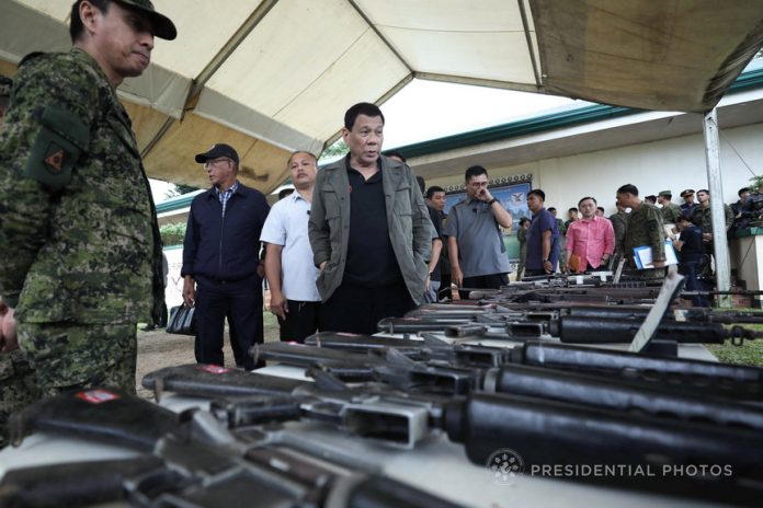 EXAMINING SEIZED GUNS. President Rodrigo Duterte examines the firearms recovered from the communist rebels on the sidelines of the establishment of the TienDA Para sa mga Bayani at Camp General Manuel Yan in Mawab Sr. in Mawab Compostela Valley Province on Monday. Joining the President are 10th Infantry Division Commander Major General Noel Clement, Defense Secretary Delfin Lorenzana and Special Assistant to the President Christopher Lawrence Go. PRESIDENTIAL PHOTO