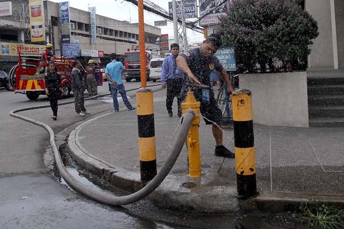 ASSURED.A member of Central 911 firefighting team closes the valve of a fire hydrant at the junction of Gen. Luna Street and R. Magsaysay Avenue after a fire that hit a hardware has been declared under control on Thursday. LEAN DAVAL JR.