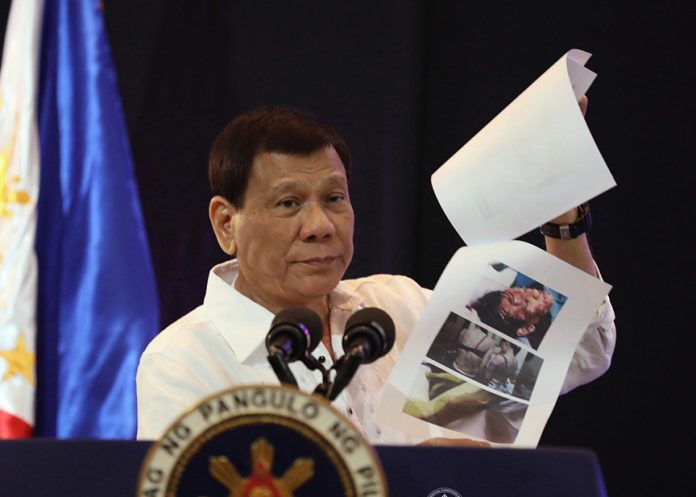 TOUCHED BY OFWS’ PLIGHT. An infuriated President Rodrigo Duterte, in his speech during the Manila Times 7th Business Forum at the Marco Polo Hotel in Davao City on Friday night, shows photos of Overseas Filipino Workers (OFWs) who were reportedly abused in Kuwait. PRESIDENTIAL PHOTO