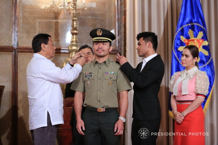 IN THE SERVICE. President Rodrigo Duterte pins the rank insignia on newly-promoted Philippine Army reserve Colonel Senator Emmanuel Pacquiao during a ceremony at the Malacañan Palace on Tuesday. PRESIDENTIAL PHOTO