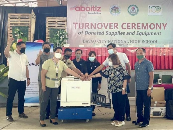 DCNHS, DepEd officials and Davao Light President and COO Rodger Velasco photocopy a school module using the donated equipment during the turnover ceremony.