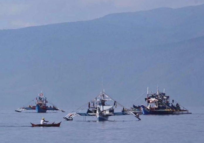 A fisherman paddles pass large fishing vessels docked near a coastal community along Pujada Bay in Mati City. Residents and environmental groups have expressed concerned on a mining operation near Pujada Bay as it may affect the seascape and landscape of one of the best bays in the world. Edge Davao