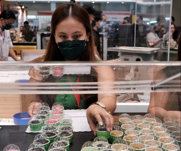 An exhibitor of a company specializing in pastry products prepares different favors of cakes on small cups for the visitors and onlookers during the World Food Expo Davao 2022 at SM Lanang Premier's SMX Convention Center over the weekend. Edge Davao