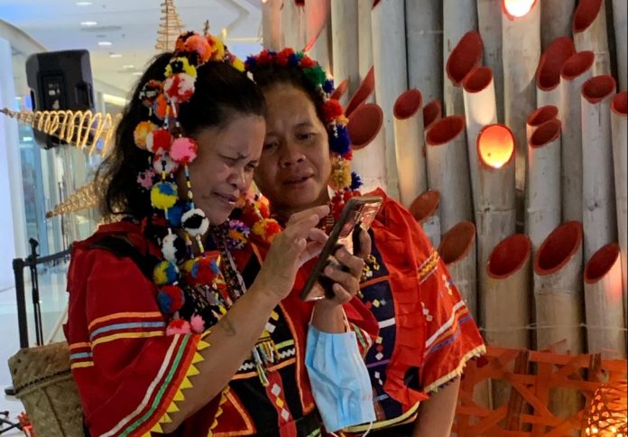 Women belonging to the Matigsalug ethnic group look at their photos taken with Abreeza Mall's bamboo Christmas tree as background from a mobile phone at Abreeza Mall in Davao City. Edge Davao