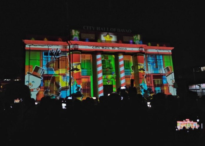 Dabawenyos gather at Quezon Park to watch the Christmas 3D Wall Mapping that illuminates the Davao City Hall during the Dan-ag sa Pasko ug Pag-abli sa Pasko, the opening ceremony of Pasko Fiesta sa Davao 2022, in Davao City on Thursday evening. Lean Daval Jr.