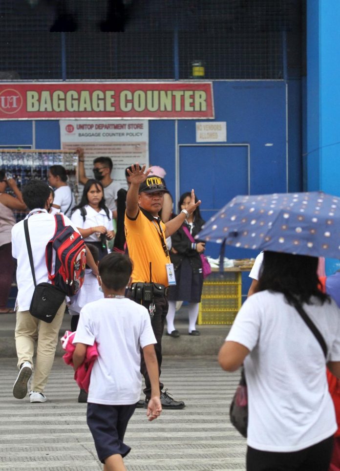 A personnel of the City Transport and Traffic Management Office (CTTMO) mans the traffic to let the pedestrian, which are mostly elementary students, safely cross a very busy San Pedro Street in Davao City on Friday. LEAN DAVAL JR.