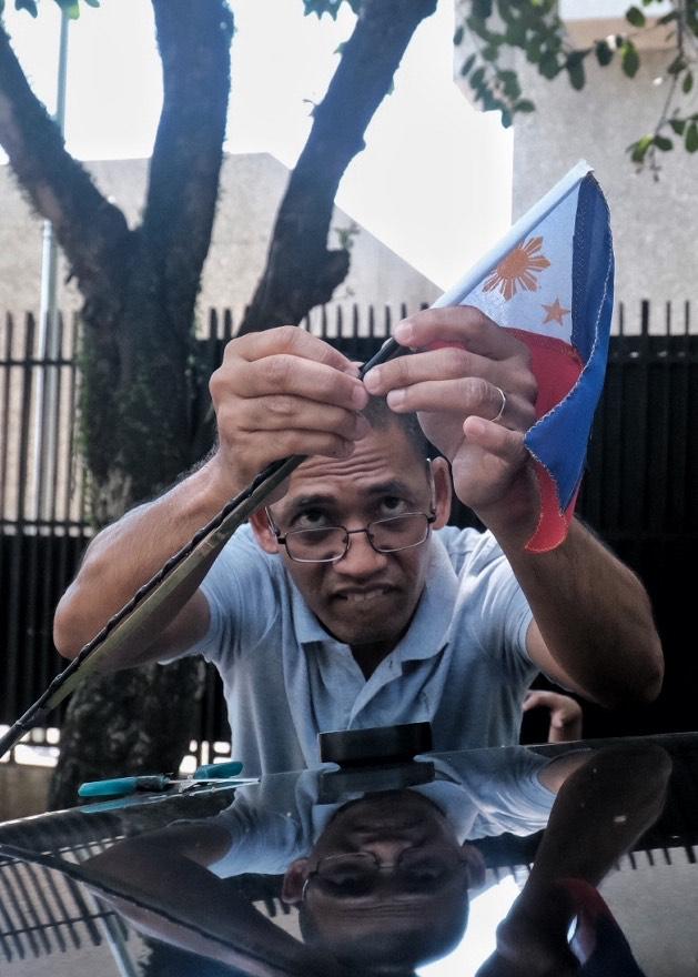 A motorist attaches a miniature Philippine flag, which he just bought from a hawker, to his vehicle along Tionko Avenue in Davao City on Saturday ahead of the celebration of the 125th Philippine Independence Day on Monday. LEAN DAVAL JR