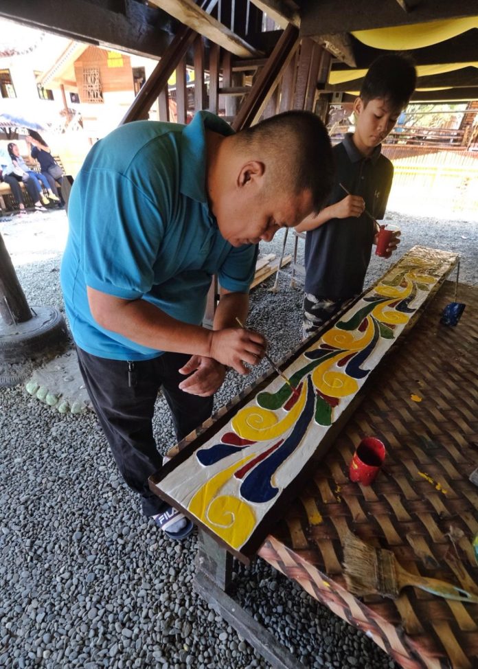 Men belonging to the Maranao ethnic group paint the okir, an important component of a traditional Maranao royal house called 