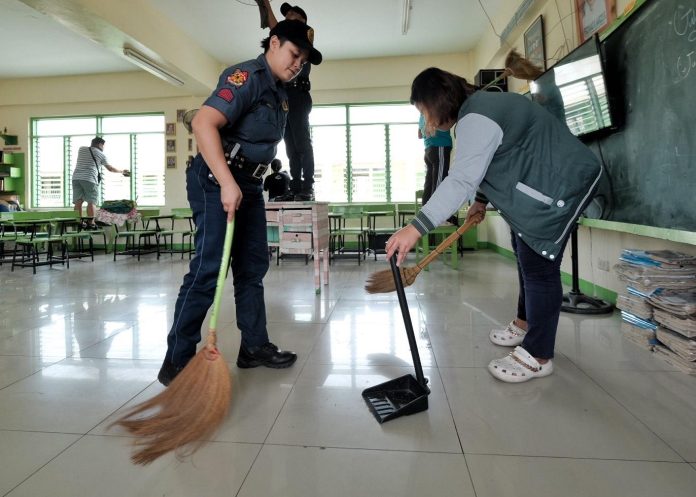 A police officer participates in cleaning a classroom at San Roque Central Elementary Scool in Bo. Obrero, Davao City during the first day of Brigada Eskwela 2023 on Monday. LEAN DAVAL JR.