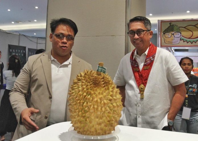 Presidential Assistant for Eastern Mindanao Secretary Leo Tereso Magno (right) and Durian Industry Association of Davao City (DIADC) president Emmanuel Balviz look at a puyat variety durian on display at one of the booths at the exhibit area of the 1st Philippine Asia Durian Summit at SMX Convention Center in Davao City on Thursday. LEAN DAVAL JR