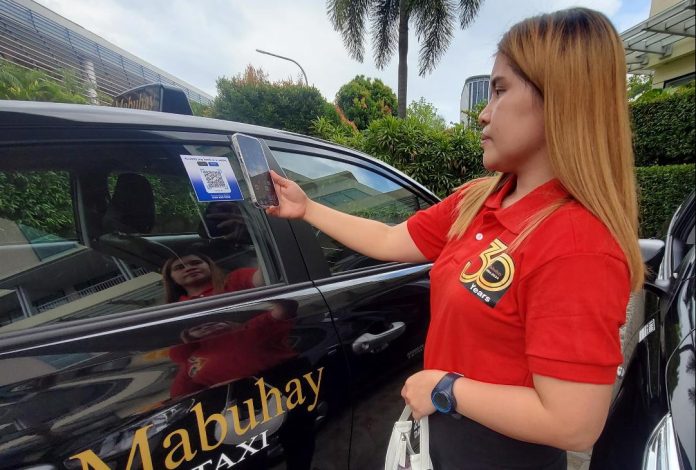 A staff of Mabuhay Taxi shows the QR code payment feature that is being introduced in the company's new taxi fleet during the launching of its initial 41 new black units in time for its 30th anniversary held at Park Inn by Radisson Davao on Thursday. LEAN DAVAL JR