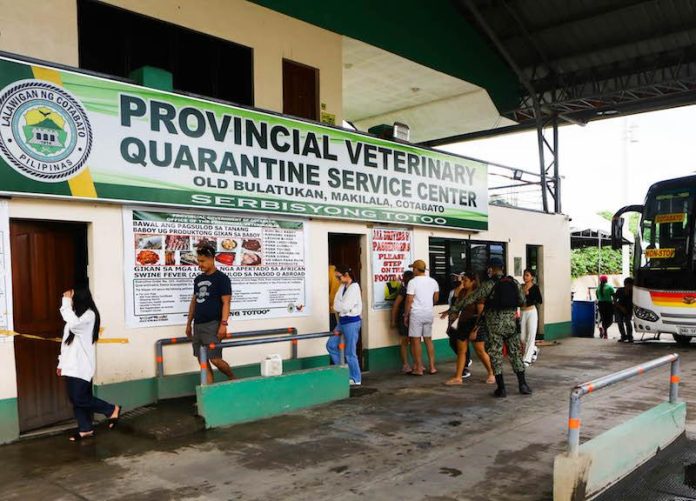 Commuters step on a foot bath at the quarantine checkpoint at Barangay Old Bulatukan in Makilala, North Cotabato on Friday. The provincial government of Cotabato tightened measures in its entry points following the newly recorded African swine fever cases in some towns of the province. Makilala is the entry point to North Cotabato from the rovince from Davao del Sur. MindaNews photo