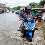 A father and his child on a motorcycle wade through a flooded road in Matina Aplaya in Davao City on their way to school on Thursday morning. MAYA PADILLO