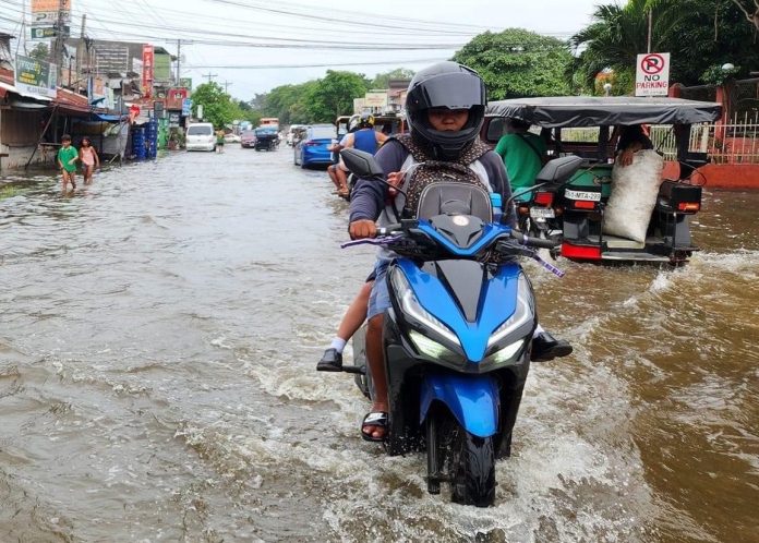 A father and his child on a motorcycle wade through a flooded road in Matina Aplaya in Davao City on their way to school on Thursday morning. MAYA PADILLO