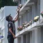 A man uses a wooden stool as he offers flowers to his departed loved one's grave located at the top level of one of the apartment tombs at the Wireless Cemetery along Father Selga Street in Davao City ahead of All Saints' Day and All Souls' Day observance. LEAN DAVAL JR