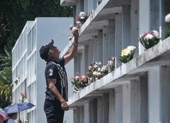 A man uses a wooden stool as he offers flowers to his departed loved one's grave located at the top level of one of the apartment tombs at the Wireless Cemetery along Father Selga Street in Davao City ahead of All Saints' Day and All Souls' Day observance. LEAN DAVAL JR