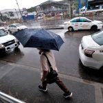 A pedestrian shileds himself with an umbrella during a rainy Friday morning outside a mall along Quimpo Blvd. in Davao LEAN DAVAL JR