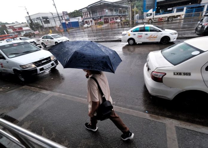 A pedestrian shileds himself with an umbrella during a rainy Friday morning outside a mall along Quimpo Blvd. in Davao LEAN DAVAL JR